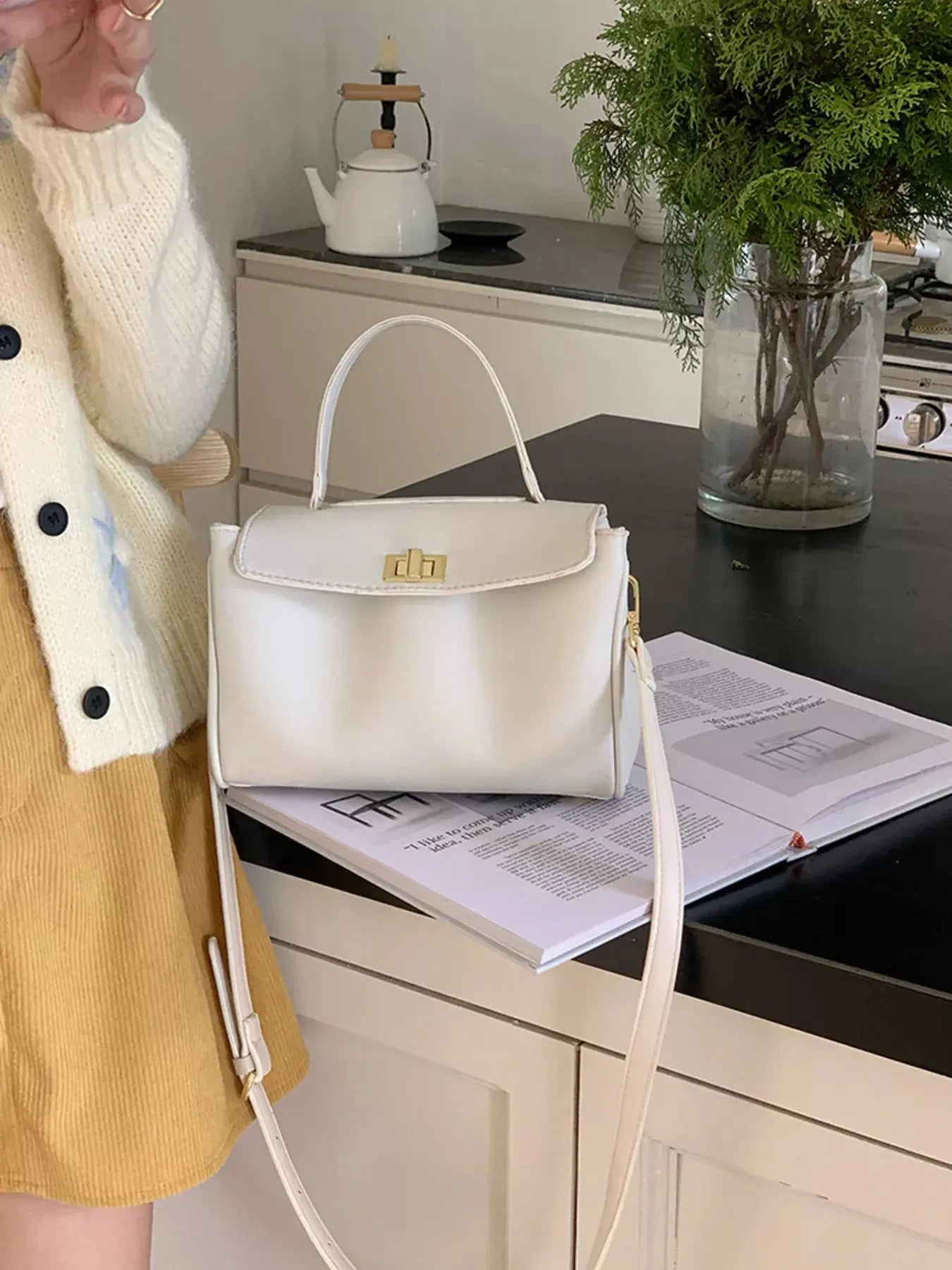 Gold twist-lock structured crossbody bag styled on model