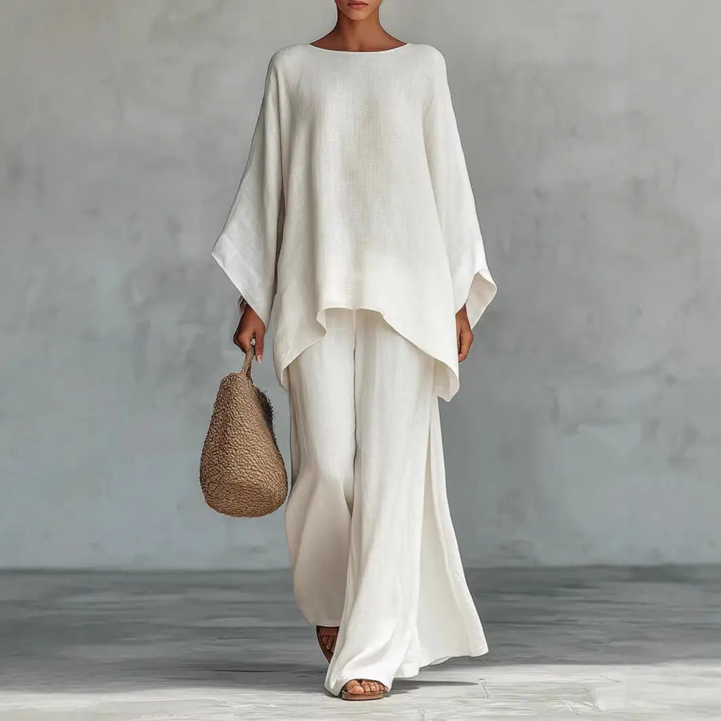Person wearing a white outfit holding a woven bag against a gray background