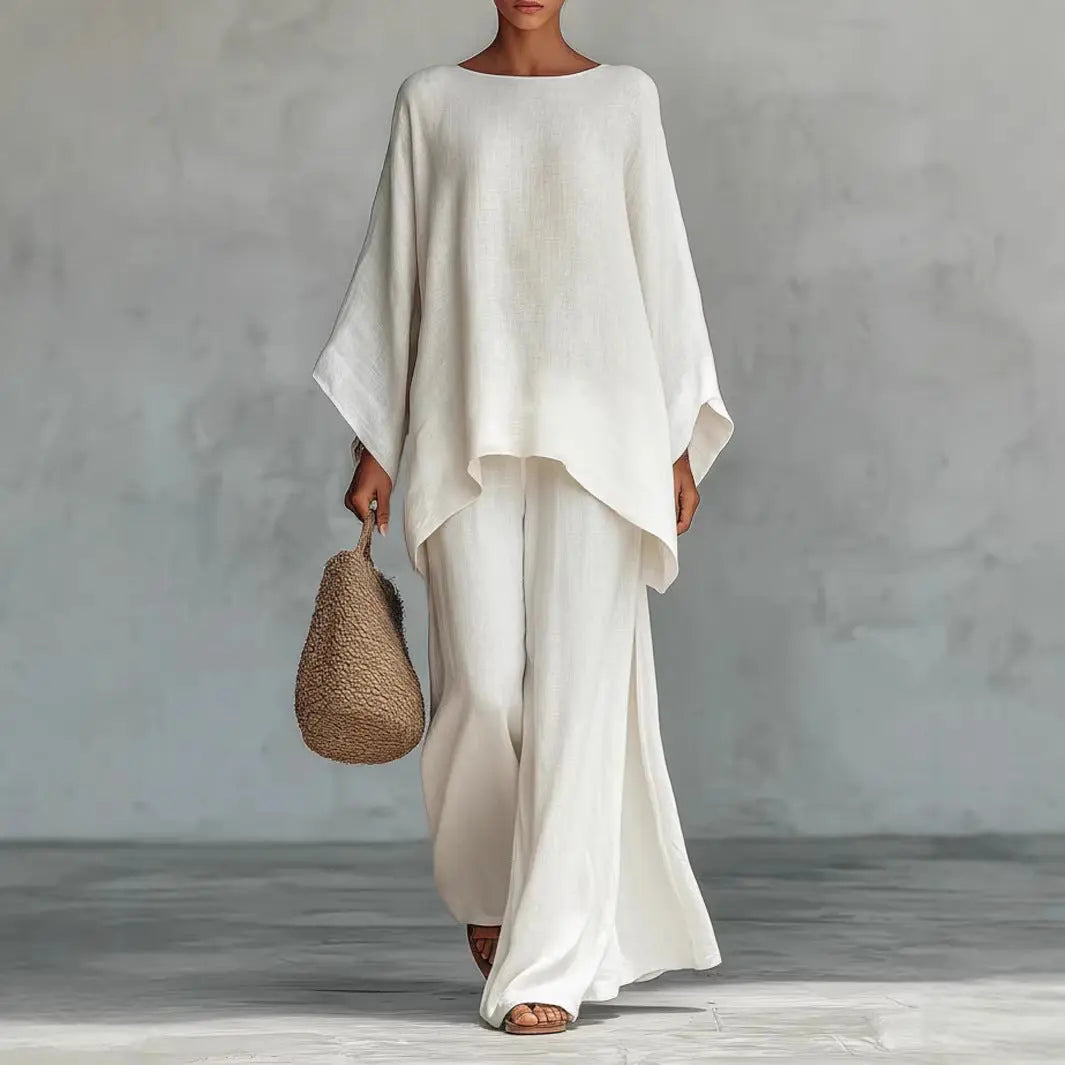 Person wearing a white outfit holding a woven bag against a gray background