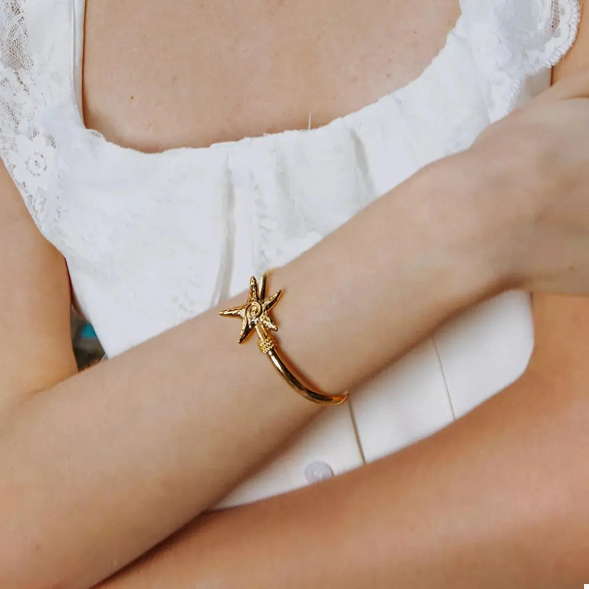 Close-up of starfish charm on gold open bracelet