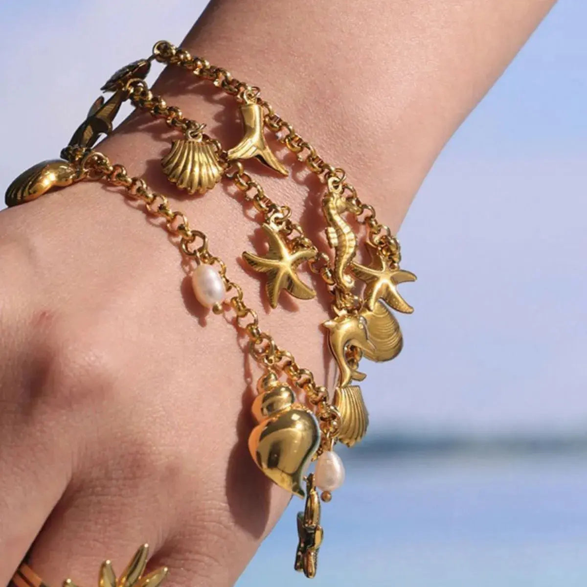 Close-up of sea shell charm on gold bracelet