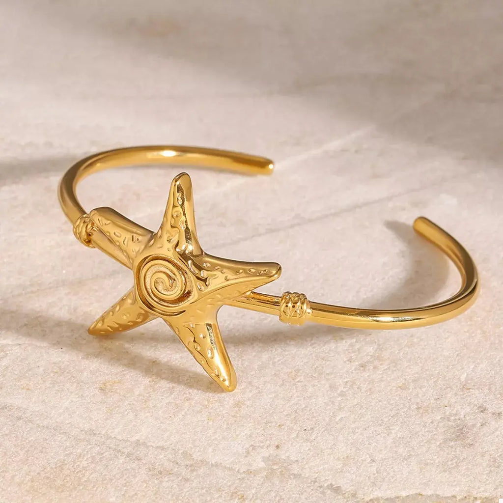 Woman wearing gold starfish open bracelet