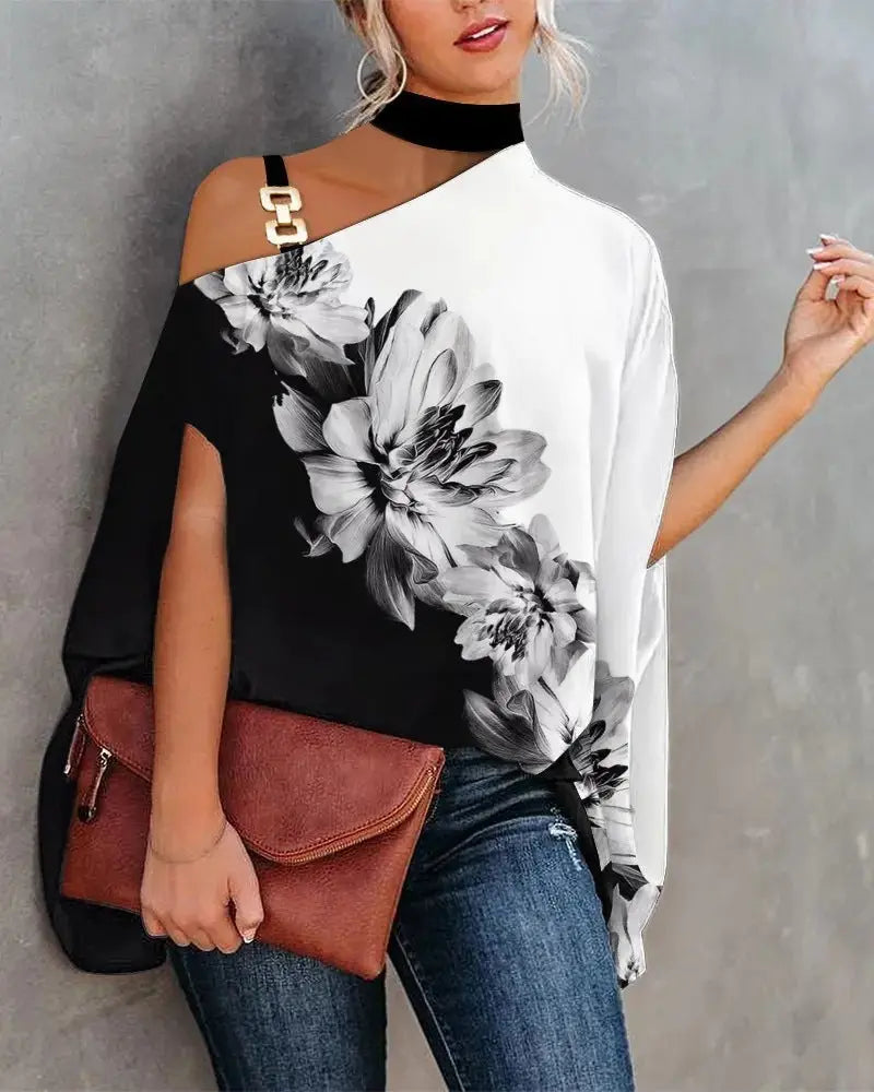 Woman wearing a black and white floral top with a brown clutch against a gray background