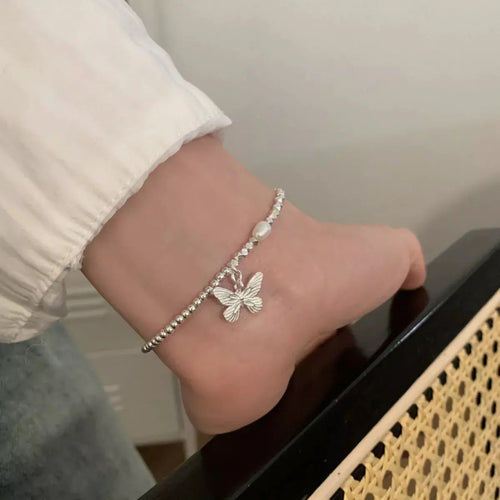 Close-up of pearl and butterfly detail on silver bracelet