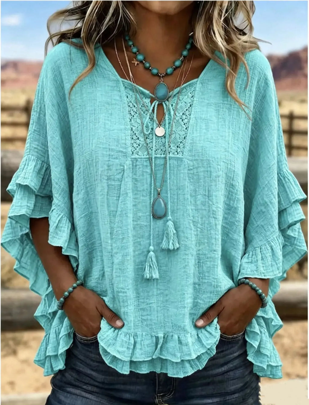 Teal blouse with ruffled sleeves and lace details worn by a person outdoors.