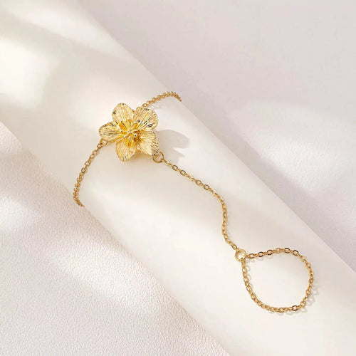 Close-up of flower charm on gold chain bracelet