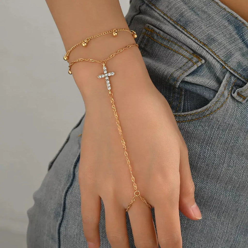 Close-up of cross charm and rhinestone detail on gold bracelet