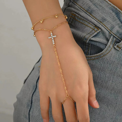 Close-up of cross charm and rhinestone detail on gold bracelet