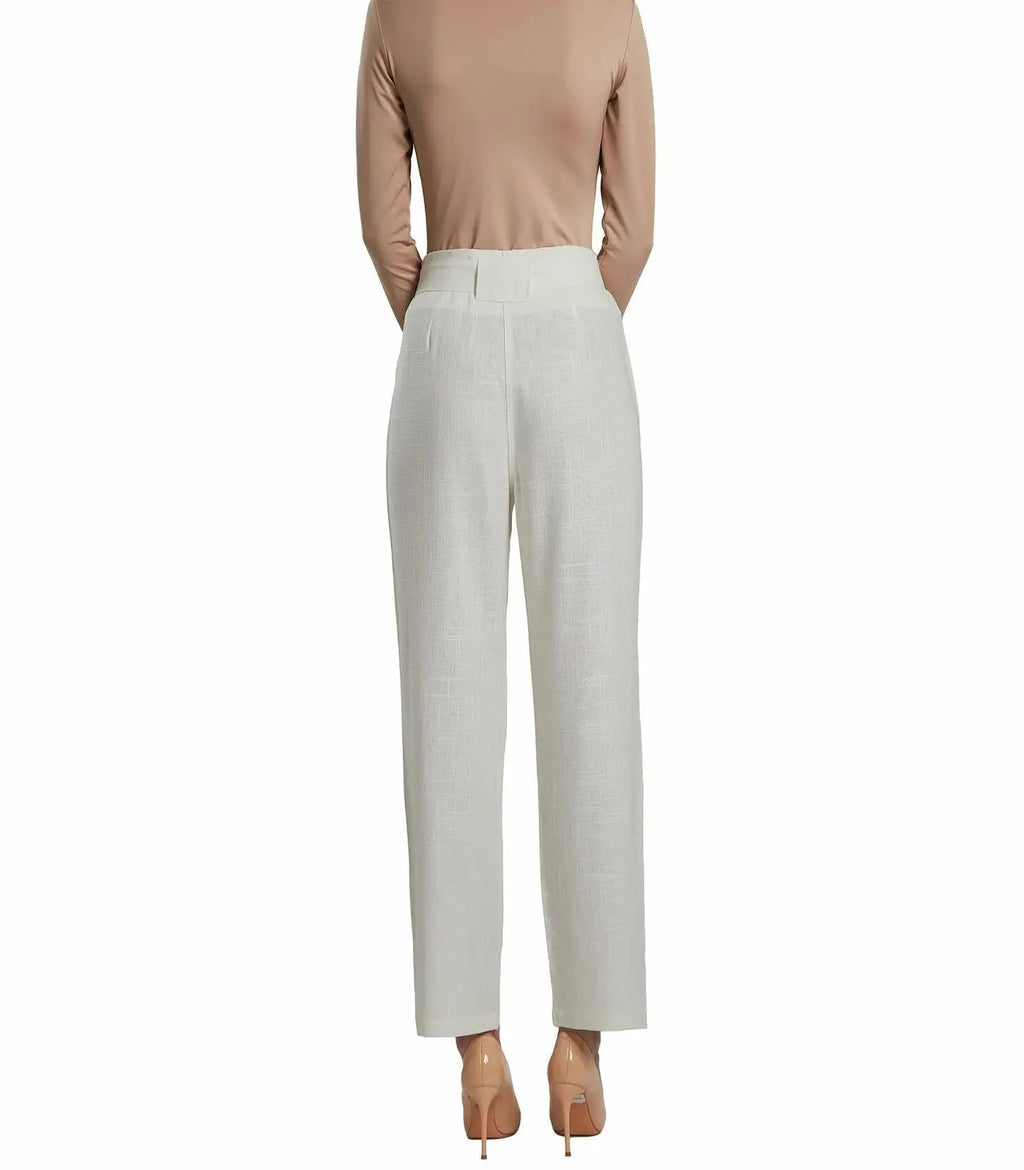 Person wearing a beige top and light gray pants on a white background