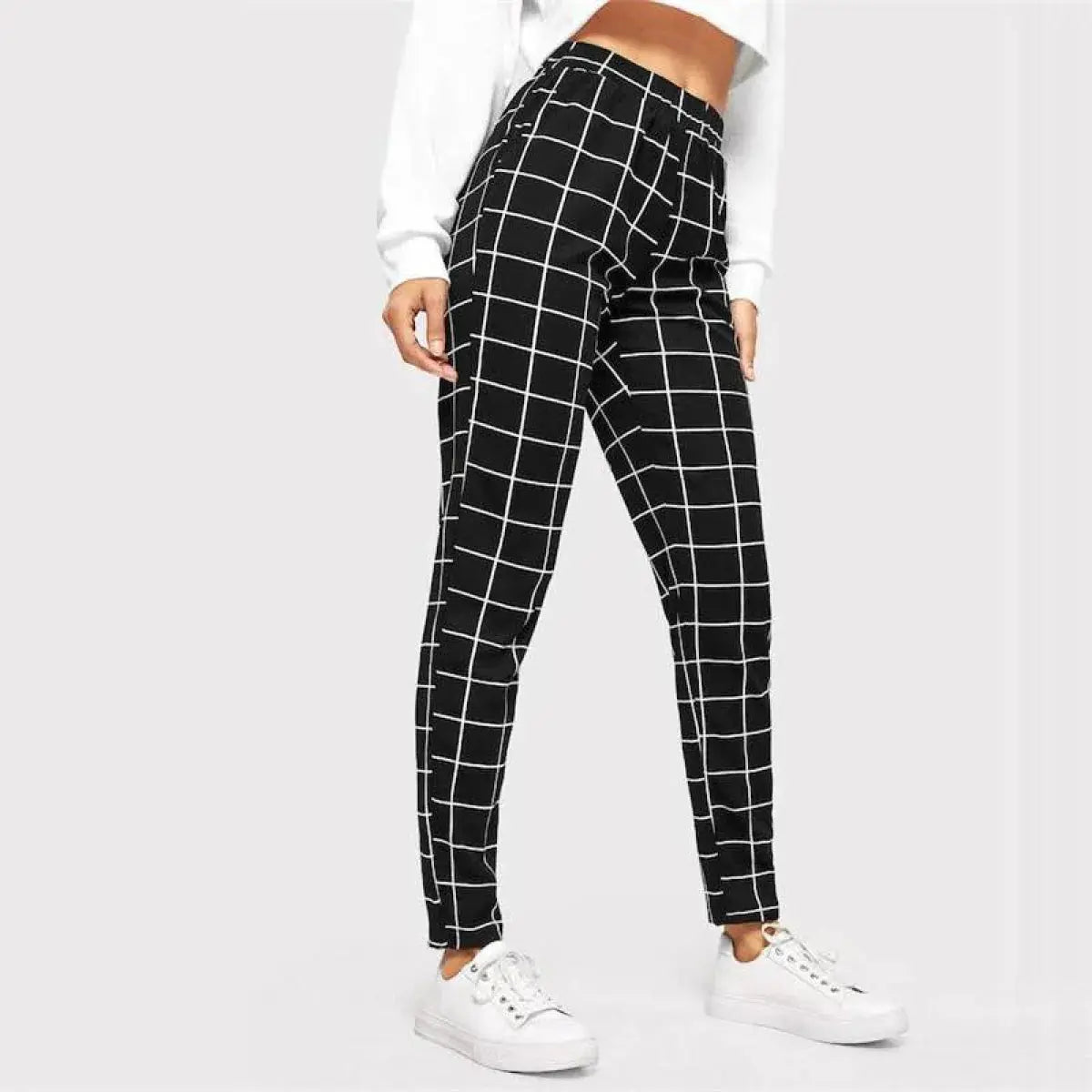Person wearing black and white checkered pants on a plain background
