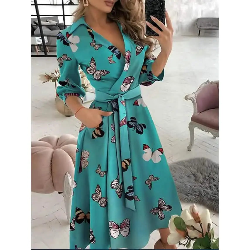 Woman wearing a turquoise dress with butterfly pattern in an indoor setting.