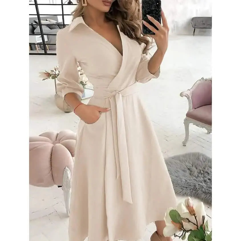 Woman wearing a white dress with a belt in a room with pink and gray furniture.