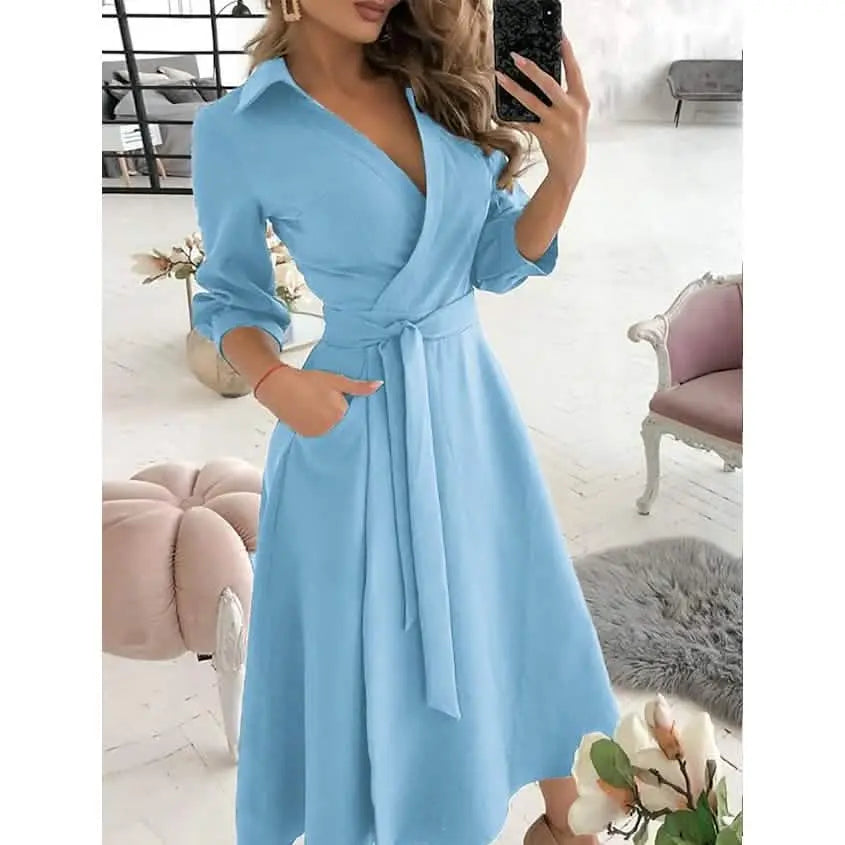 Woman wearing a light blue dress with a belt in a room with pink furniture.