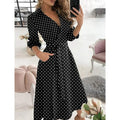 Woman wearing a black polka dot dress in a stylish room.