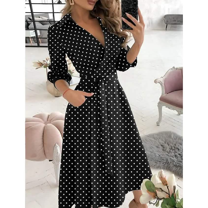 Woman wearing a black polka dot dress in a stylish room.