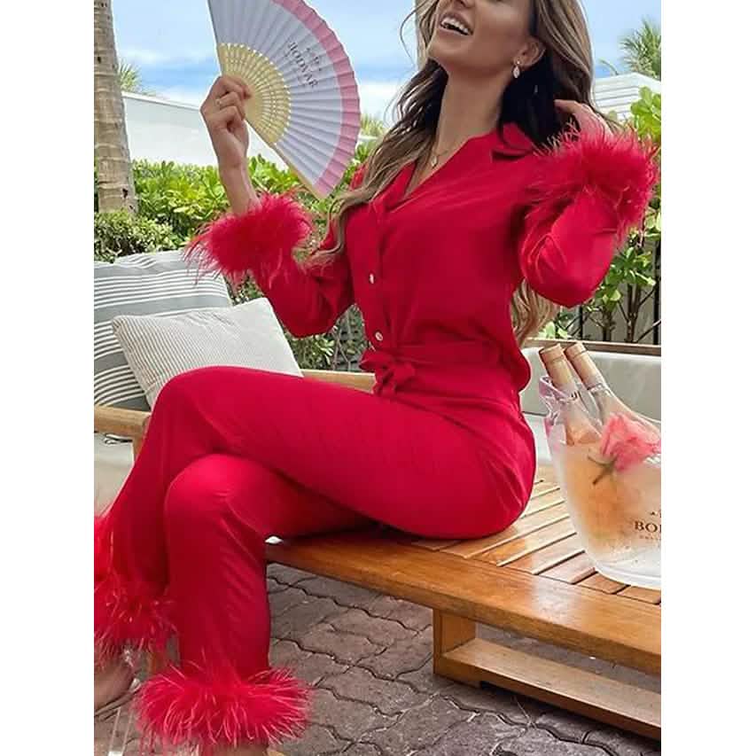 Woman in a red outfit with feathered sleeves sitting outdoors.